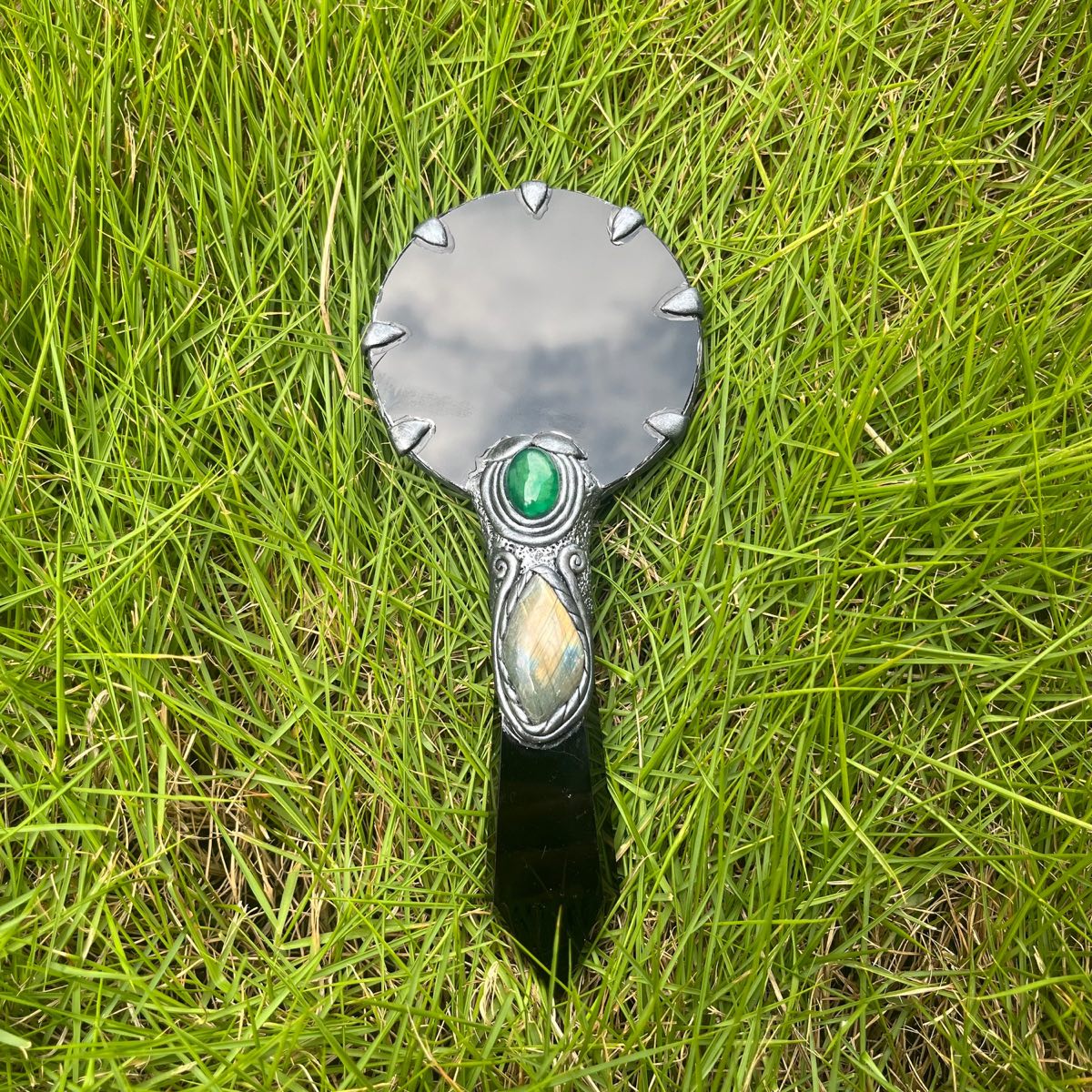 Obsidian mirror with a metal setting on grass