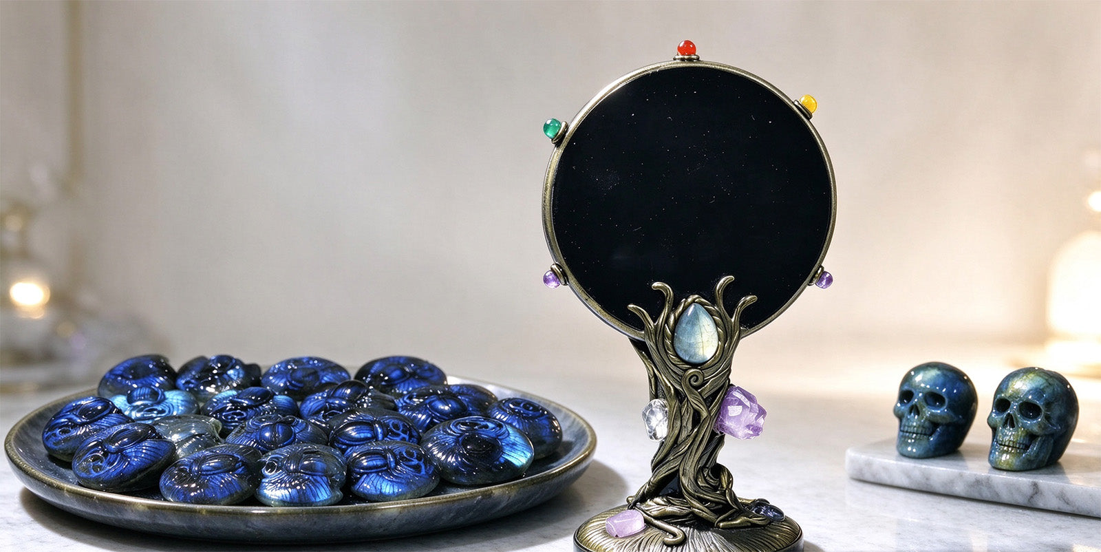 Blue carved skull stones in a dish beside a black obsidian mirror